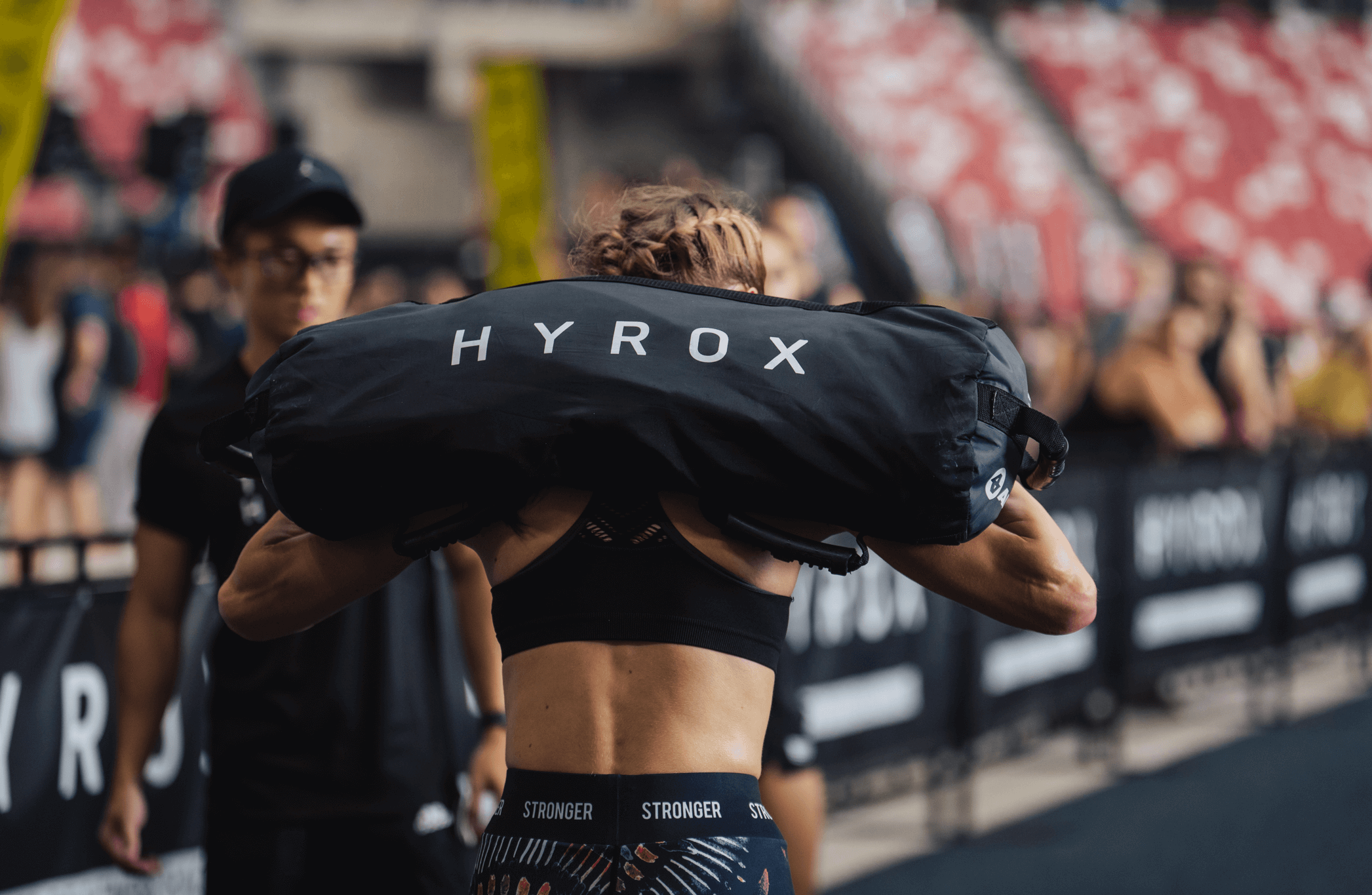 Female athlete carrying a HYROX sandbag at Melbourne competition